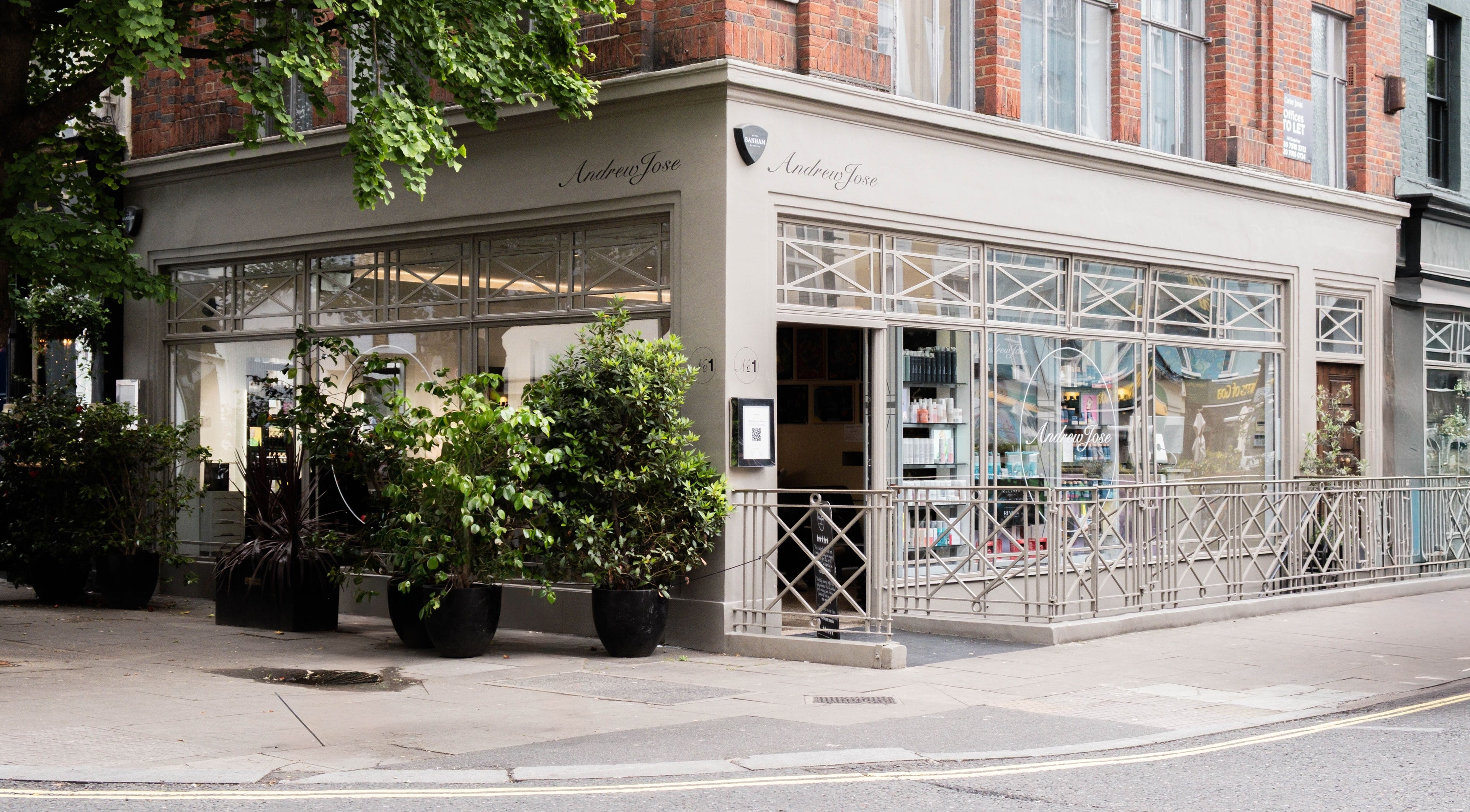 Exterior of Andrew Jose beauty salon in London, England, GB with modern window displays and greenery.