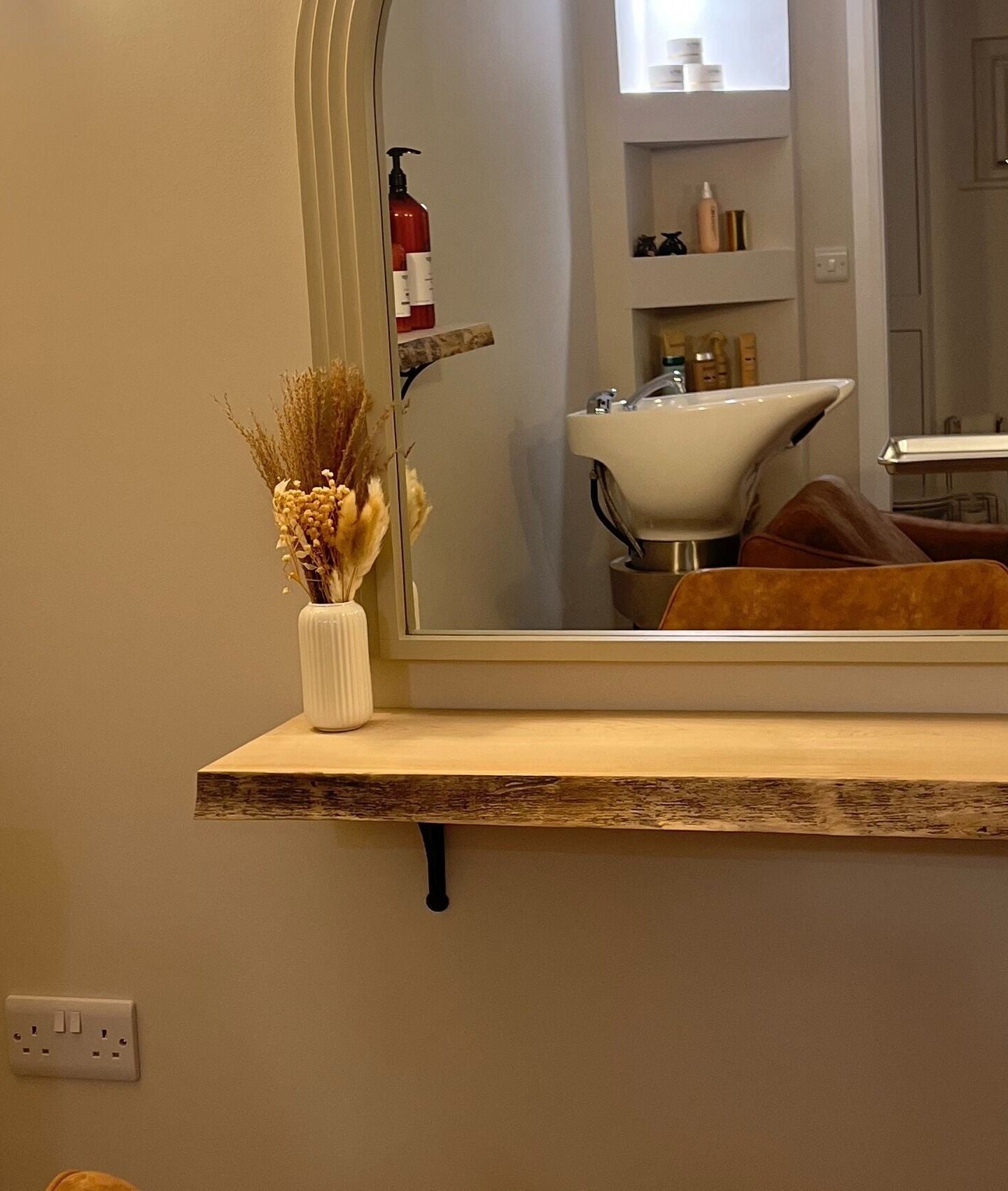 Chic salon mirror and sink at Olivia Fay, Epworth, England, GB. Elegant decor with beauty products displayed.