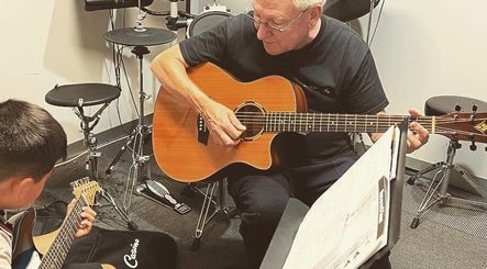 Music lesson at Michael Prizeman Music School, Melbourne, Victoria, AU with teacher and student playing guitar.