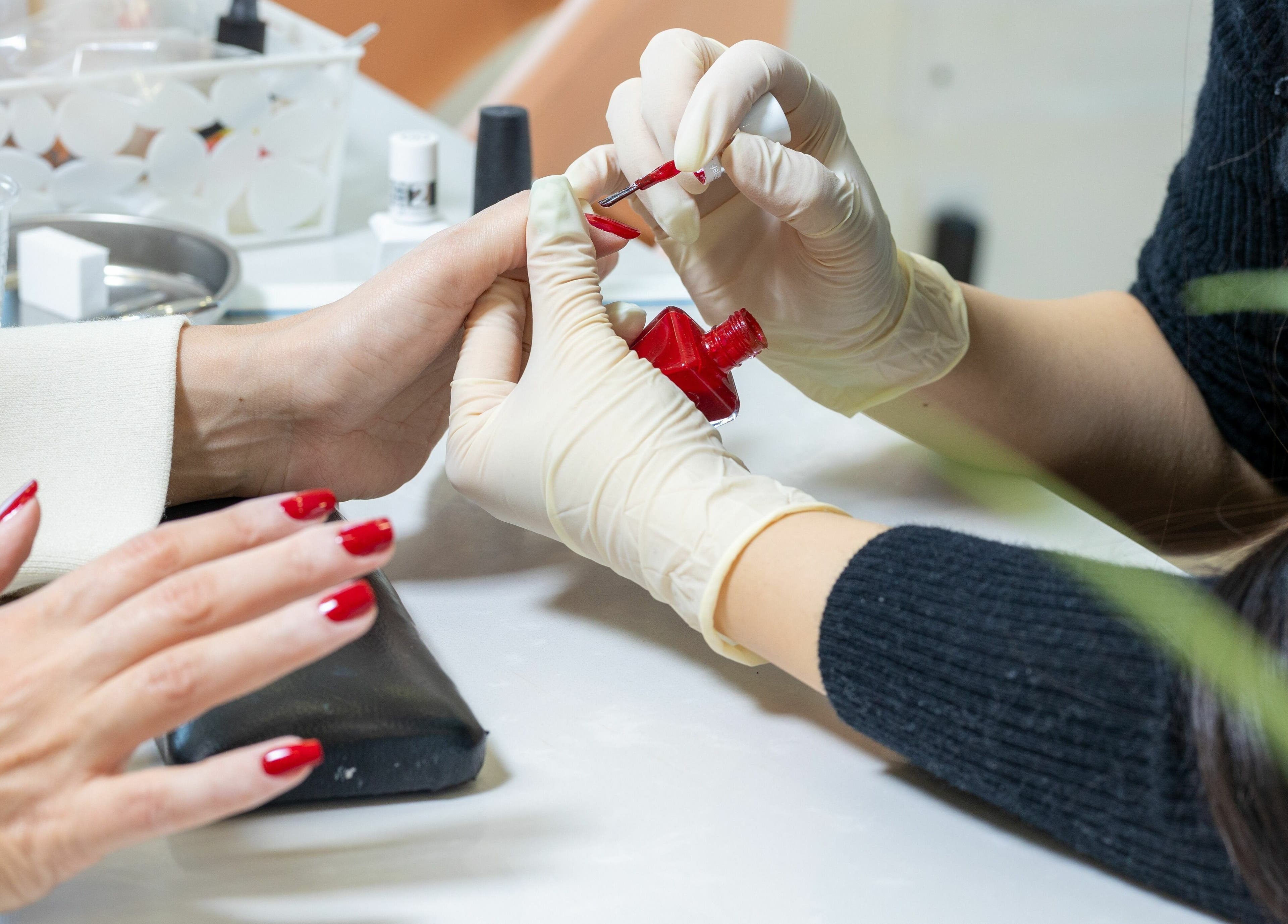 Nail artist applying red polish at Lolita Beaute, Montréal, Québec, CA. Hands with perfect manicures.
