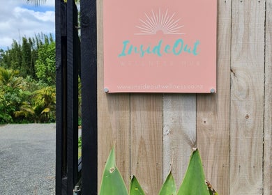 Entrance sign of Inside Out Beauty in Waipapa, Northland, NZ amidst greenery.