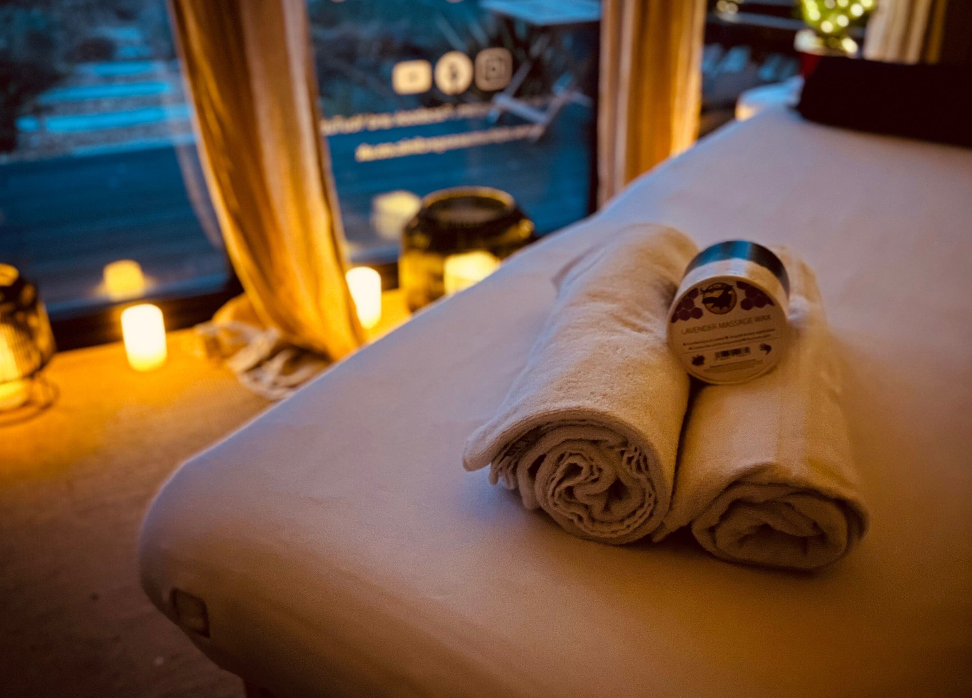 Cozy massage table setup at Alpha Massage - Chobham Clinic, Chobham, England, GB, with candles and towels.