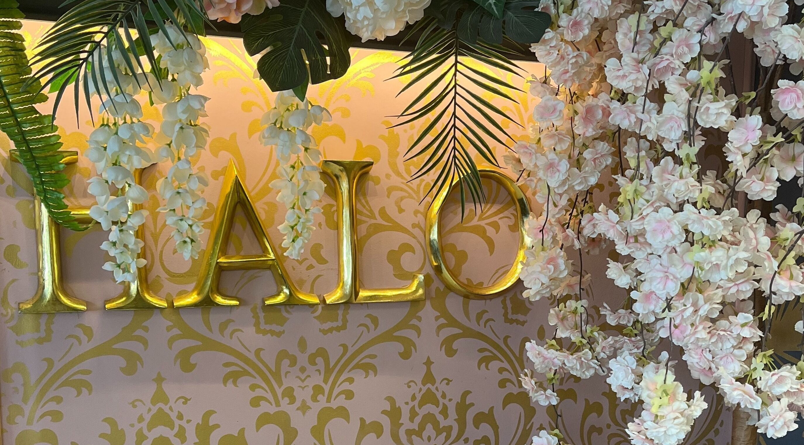 Floral decor at Halo, Newcastle-under-Lyme, England, GB, with gold lettering and lush green accents.