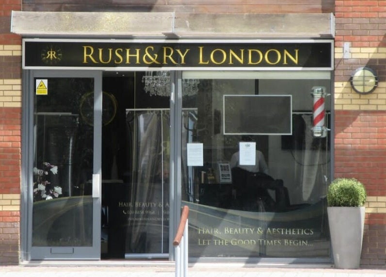 Rush&RyNorth Greenwich entrance in London, England. Modern salon with black and gold signage.