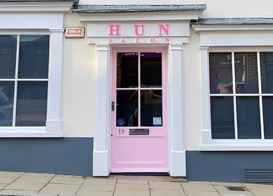 Front view of Hun Salon's vibrant pink door facade in Alton, England, GB.