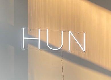 Hun Salon's stylish neon sign at Alton, England, GB, warmly illuminated in a modern setting.