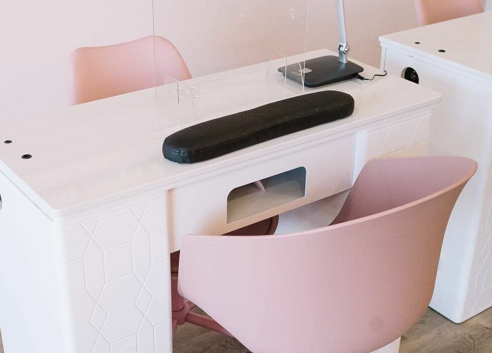 Modern manicure station at Nails & Co. Windsor, Windsor, Ontario, CA, featuring sleek design and pink chairs.