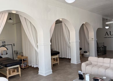 Elegant interior of Aura Beauty LLC in Kenosha, Wisconsin, US, featuring treatment stations and a cozy seating area.