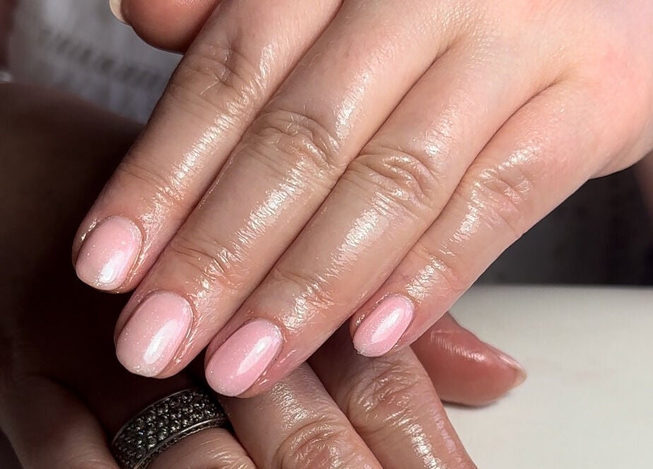 Freshly manicured hands at The Mani Lounge Cheshire in Congleton, England, GB, showcasing glossy, light pink nails.