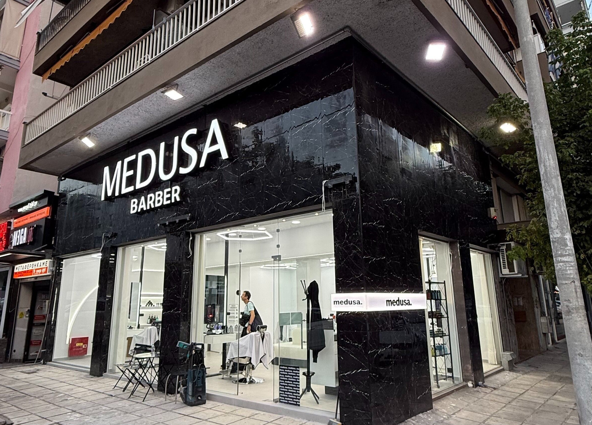 Εξωτερική πρόσοψη του Medusa Barber Kon στη Θεσσαλονίκη, GR, με φωτεινή επιγραφή.
