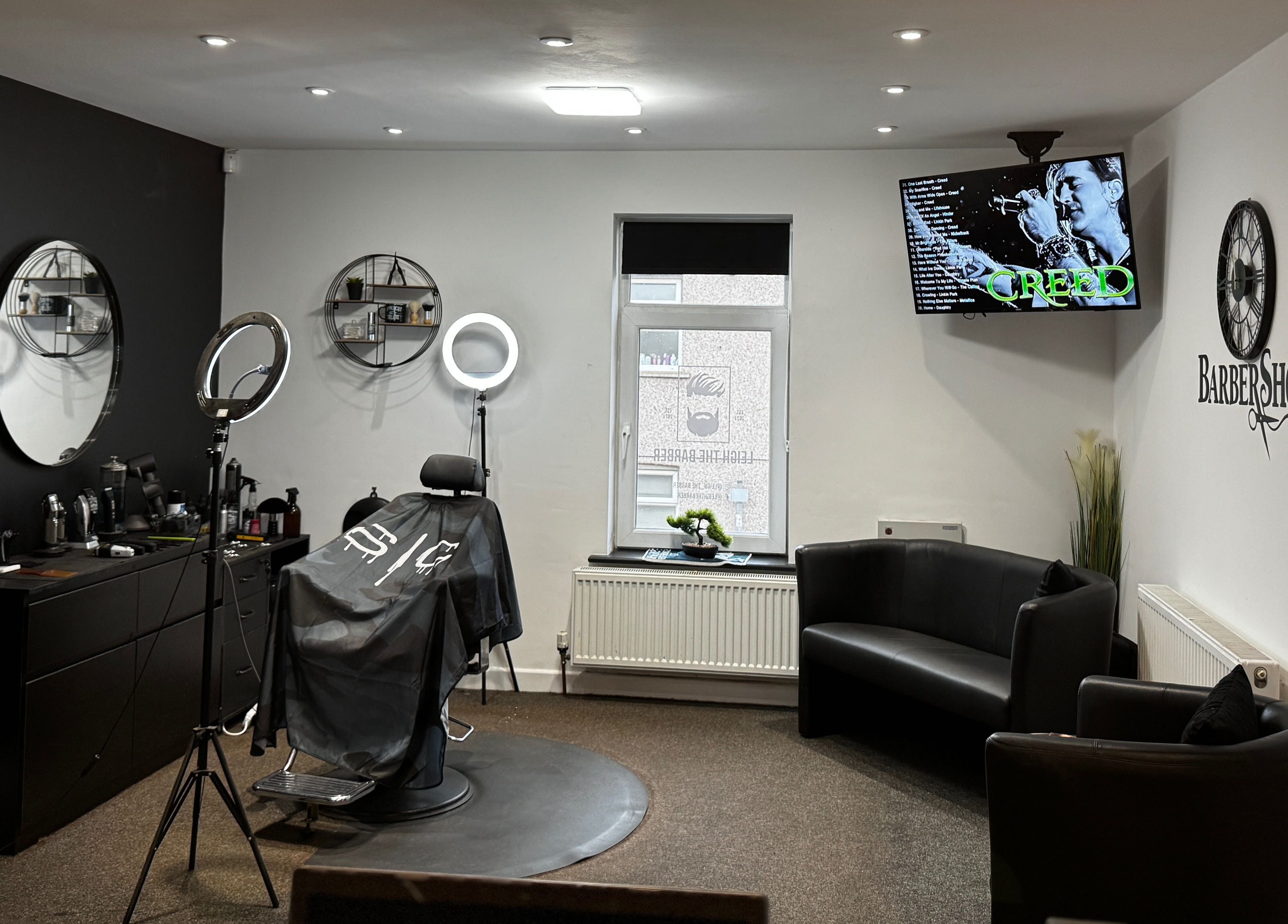 Leigh the Barber's stylish interior in Barrow in Furness, England, GB, showcasing sleek black decor and a cozy seating area.