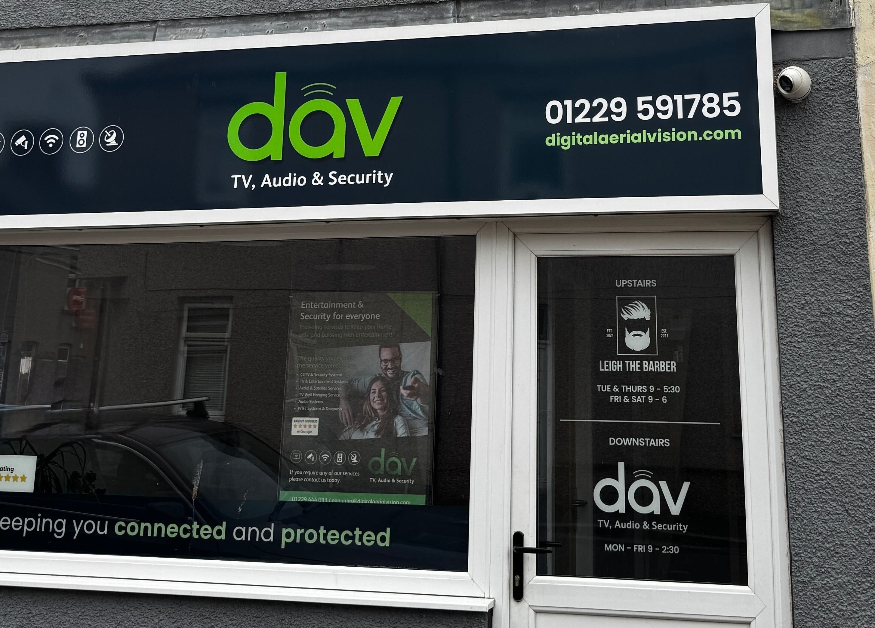 Front window of Leigh the Barber in Barrow in Furness, England, GB, showcasing services and ratings.