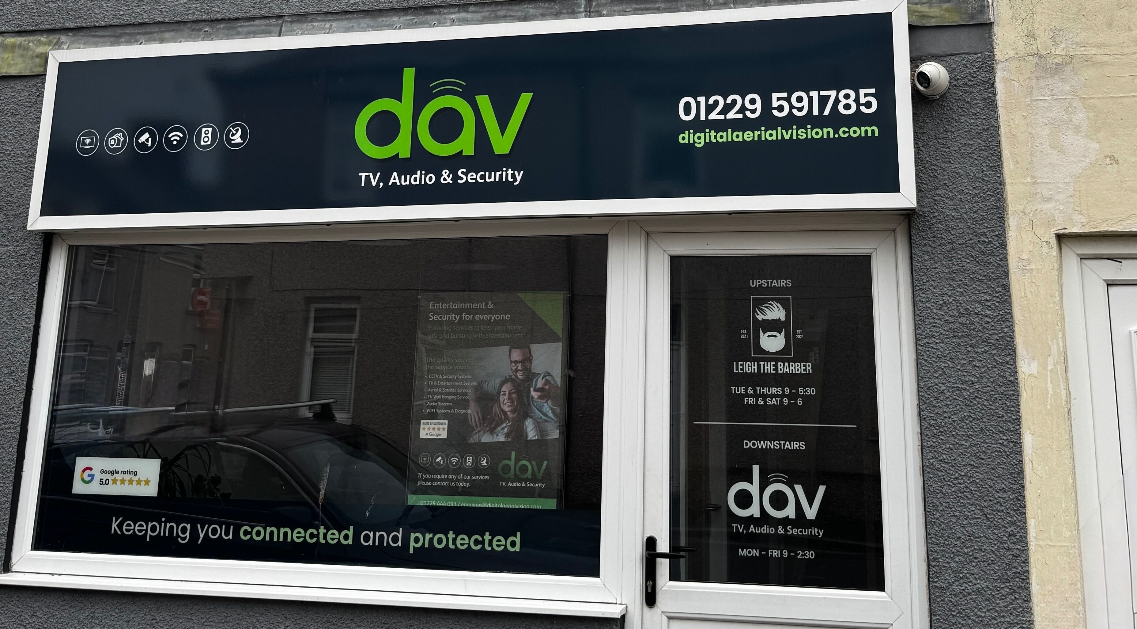 Front window of Leigh the Barber in Barrow in Furness, England, GB, showcasing services and ratings.