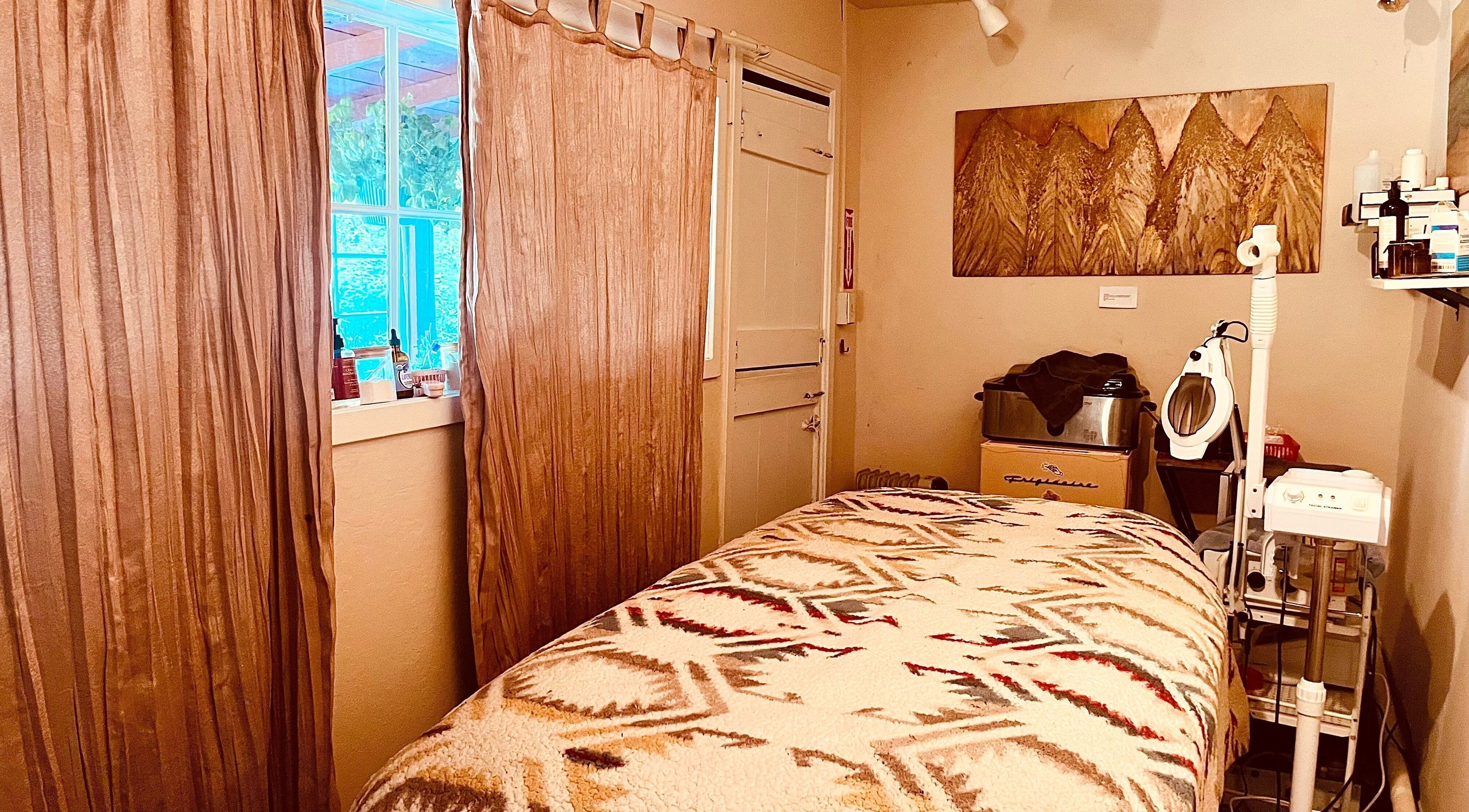 Cozy therapy room at Adorn Apothecary, Aptos, California, US with a massage table and soothing decor.