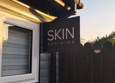 Skin Revision storefront sign in Douglas, IM, featuring a sleek design under soft evening light.