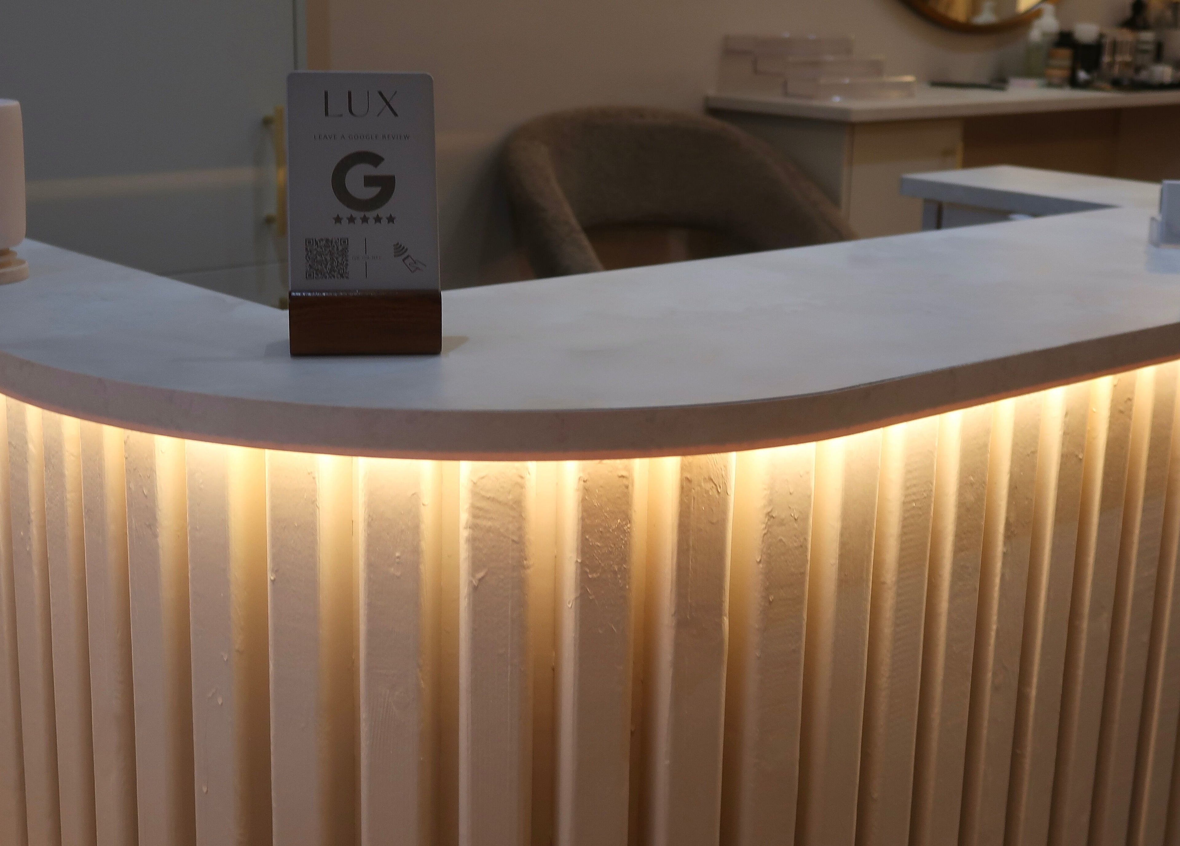 Elegant reception desk at LUX, a beauty venue in Glasgow, Scotland, GB, showcasing inviting lighting and decor.