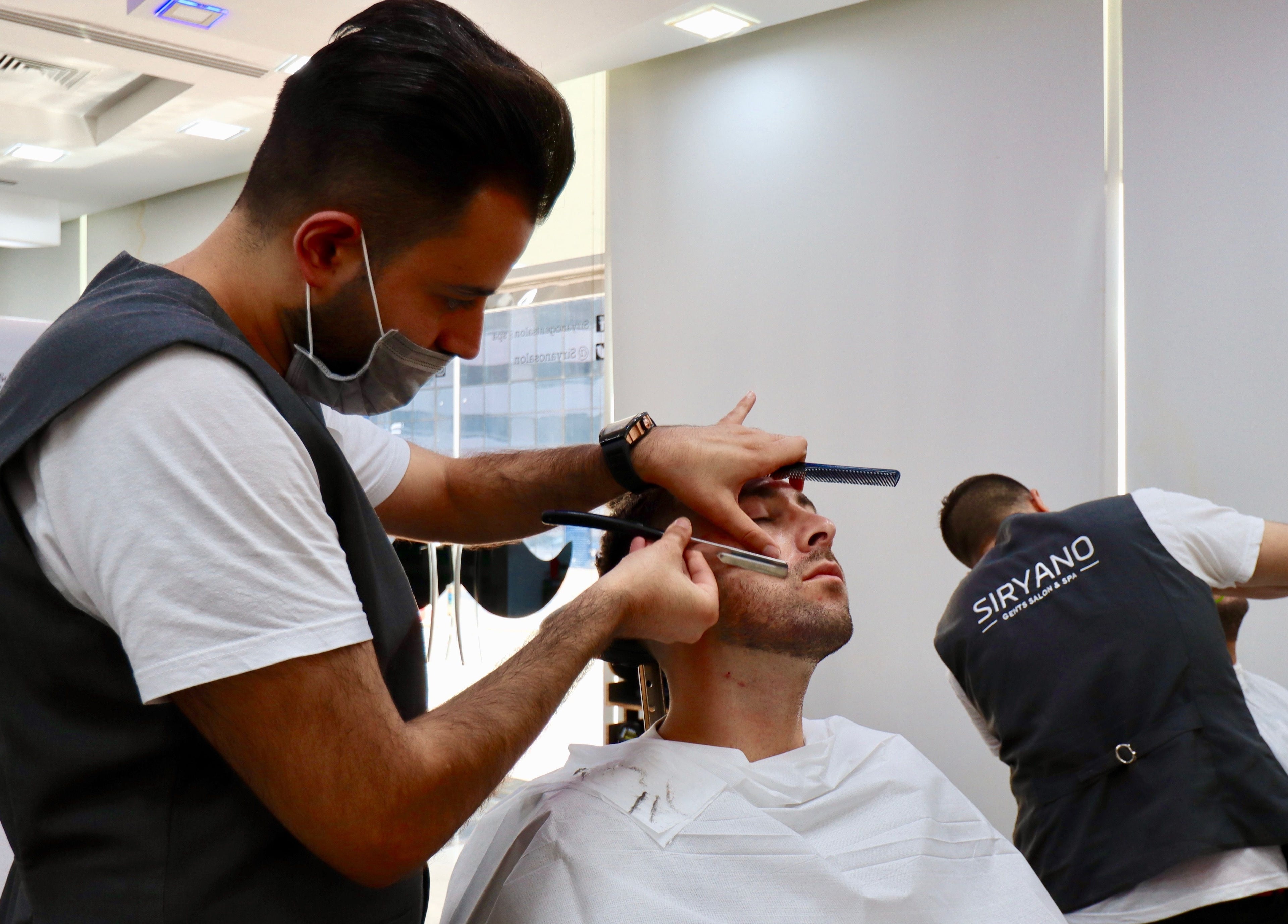 Barber at Siryano Gents Saloon and Spa, Escape Tower in Dubai, AE, expertly trims a client's beard.