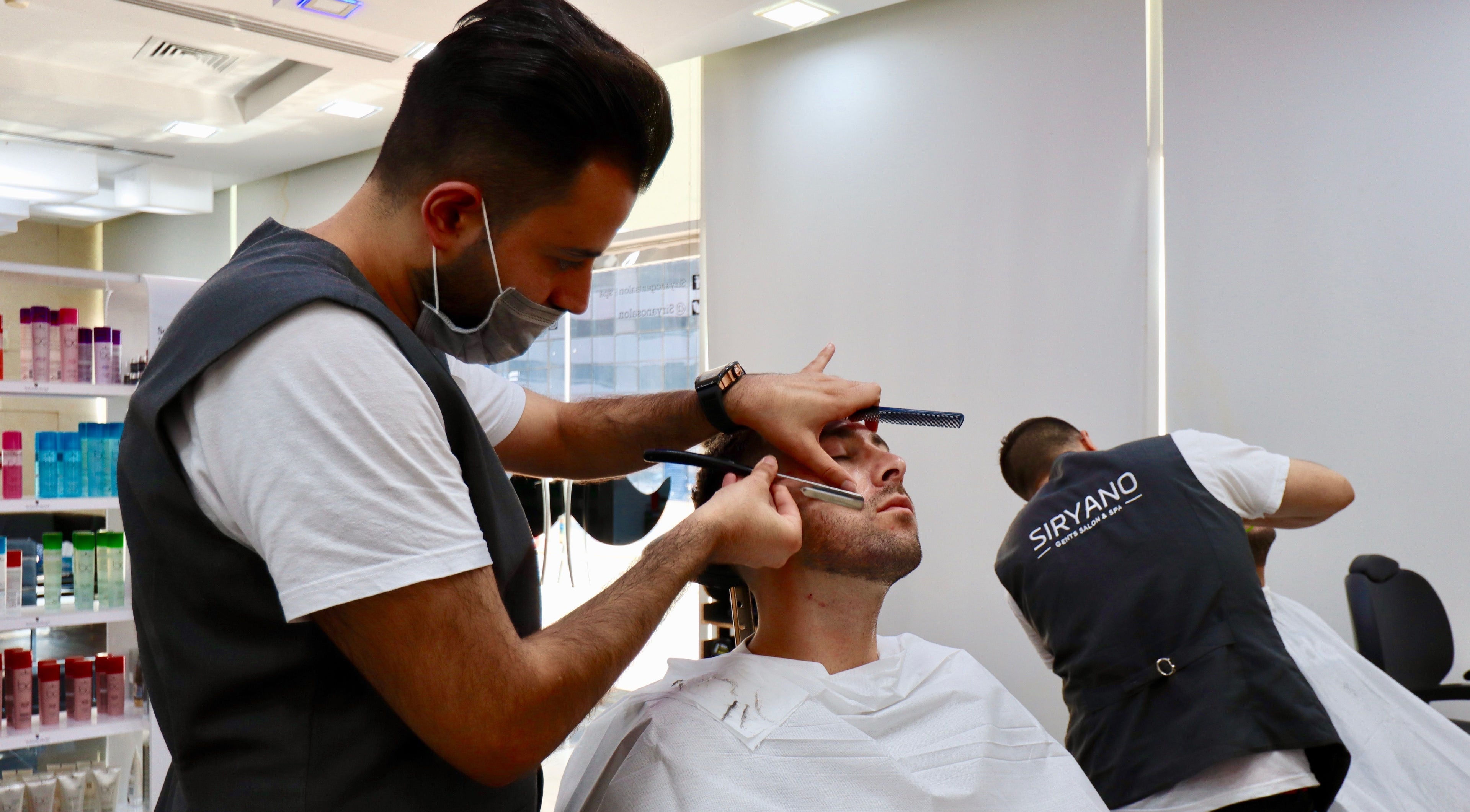 Barber at Siryano Gents Saloon and Spa, Escape Tower in Dubai, AE, expertly trims a client's beard.
