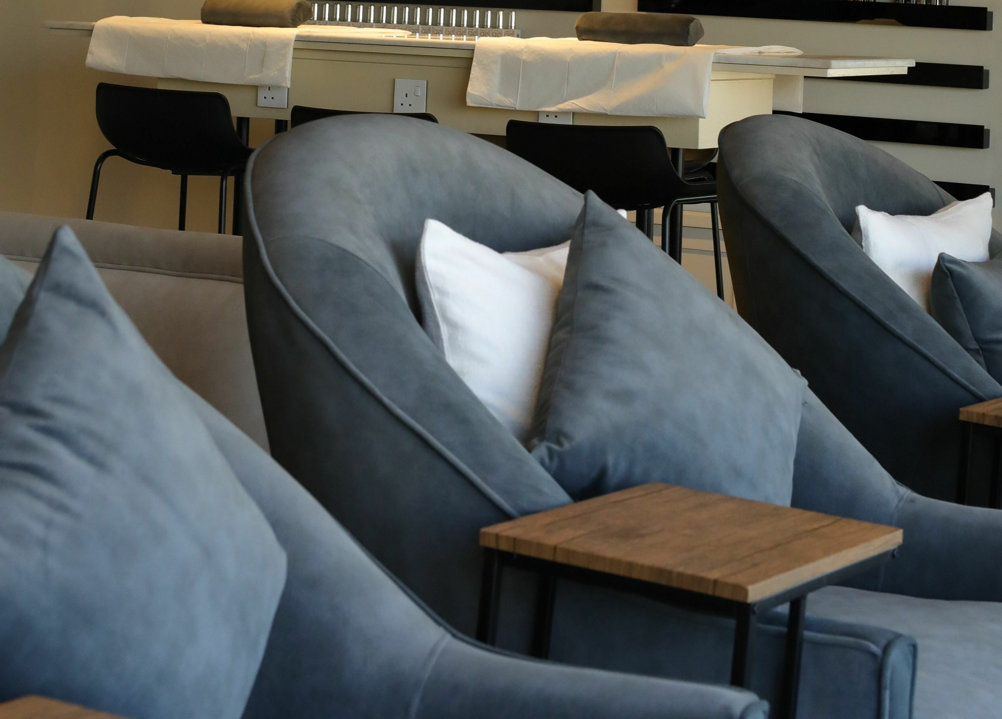 Luxurious seating at Base Coat Nail Spa, Jeddah, Makkah Province, SA, showcasing plush chairs and wooden tables.