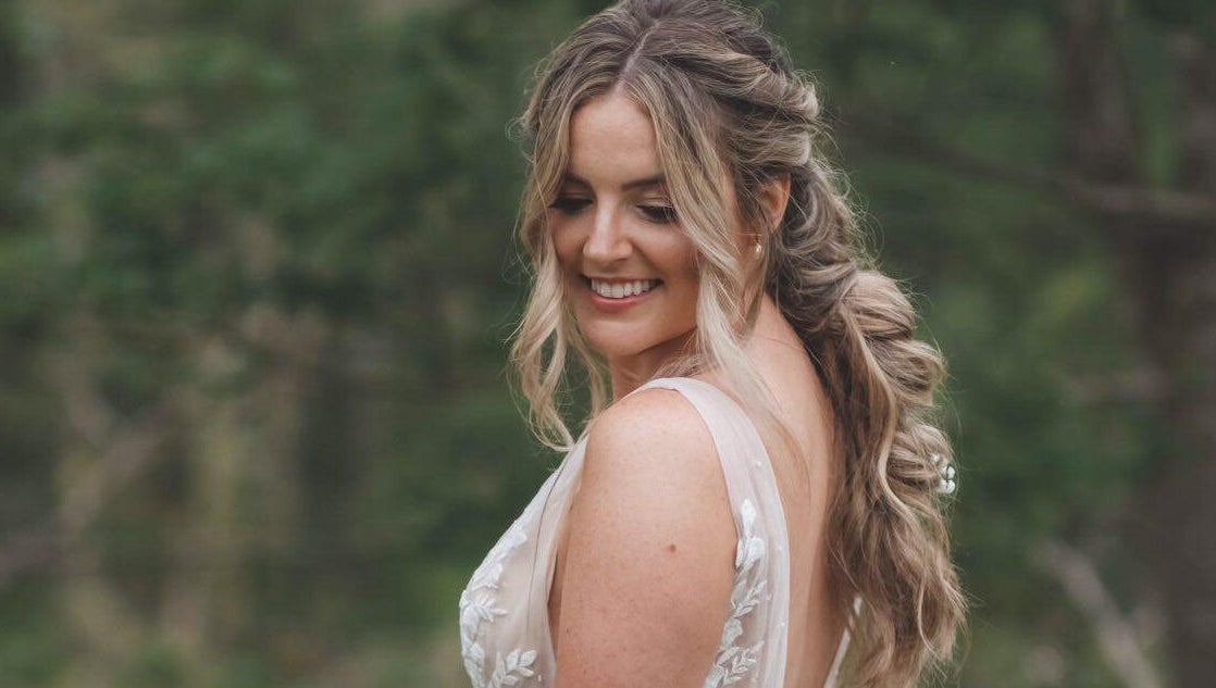 Smiling bride outdoors near All Tan Everything, Halifax, Nova Scotia, CA, showcasing elegant hairstyle.