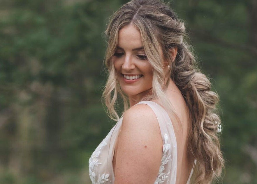 Smiling bride outdoors near All Tan Everything, Halifax, Nova Scotia, CA, showcasing elegant hairstyle.