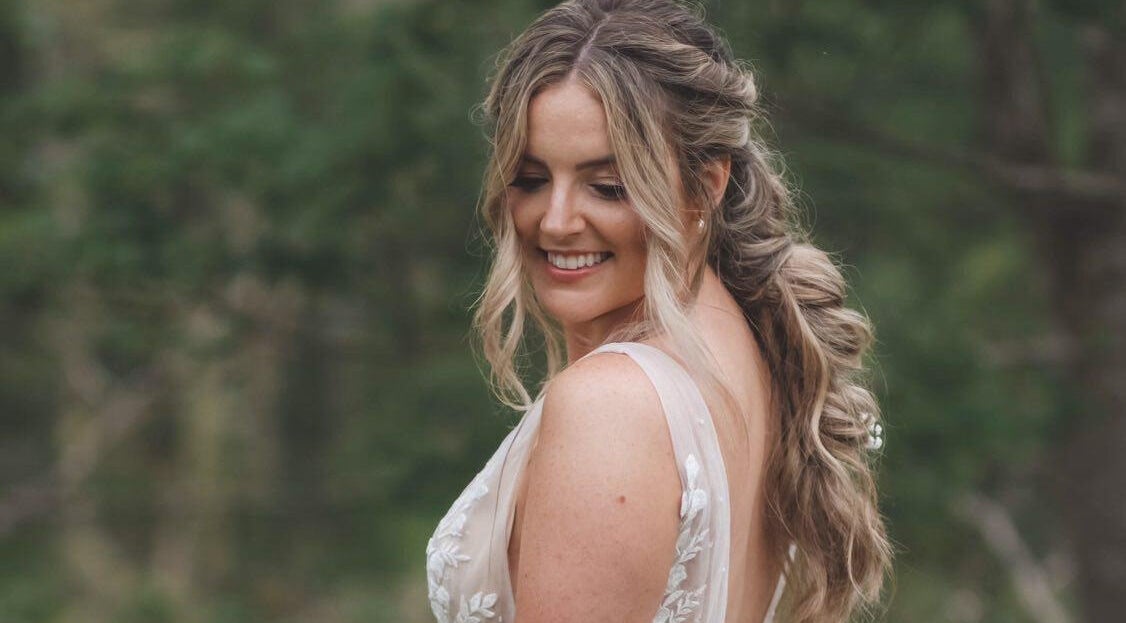 Smiling bride outdoors near All Tan Everything, Halifax, Nova Scotia, CA, showcasing elegant hairstyle.