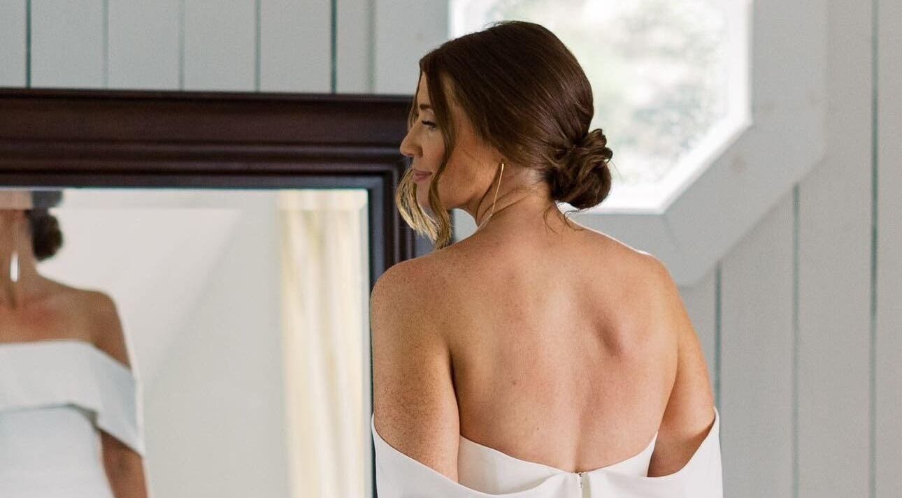 Woman in white dress looks at reflection, All Tan Everything, Halifax, Nova Scotia, CA.