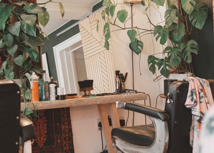 Chic salon chair and mirror at Courage Noble | King Street, Norfolk, England, GB with lush plants.