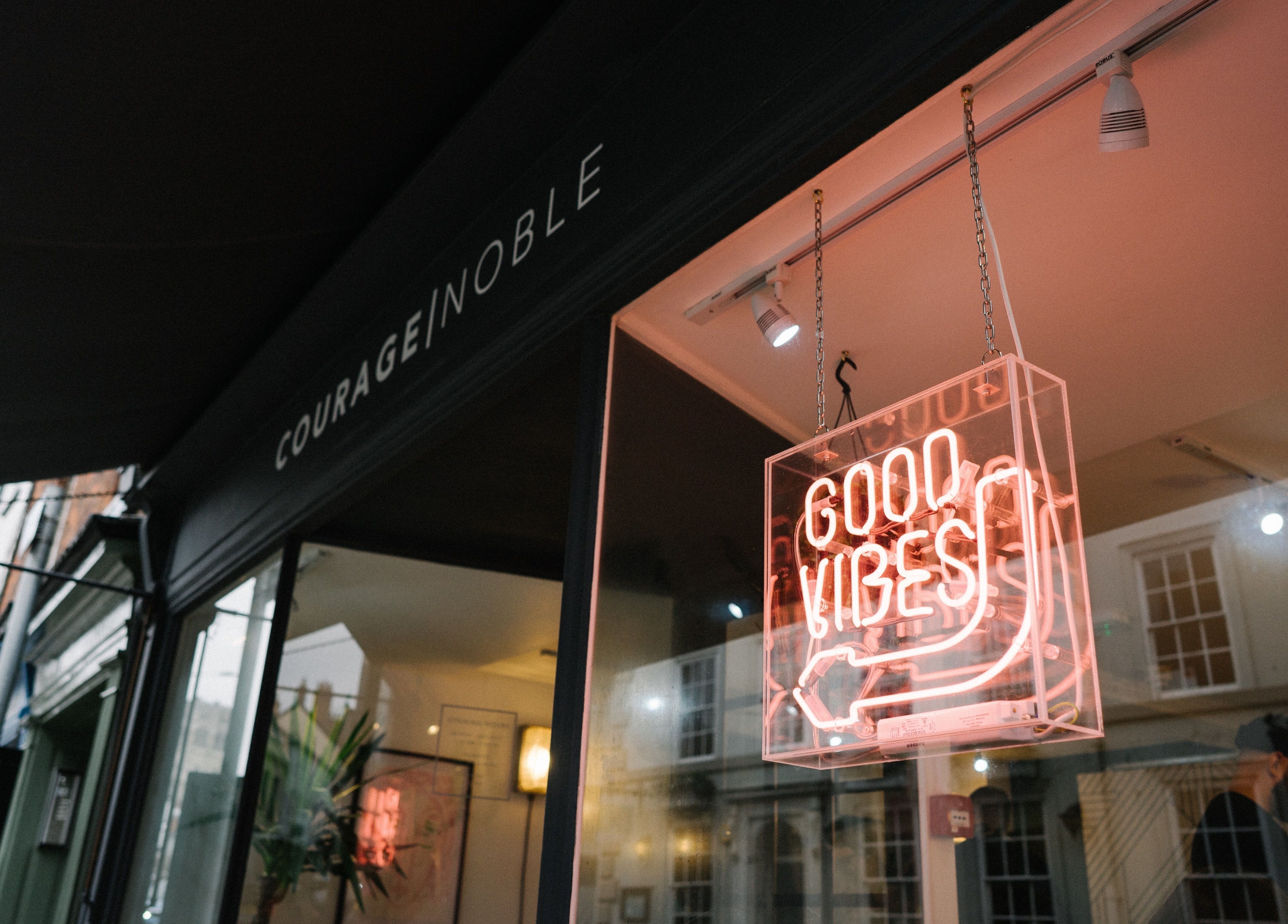 Entrance of Courage Noble | King Street, Norwich, England, GB with neon 'Good Vibes' sign.