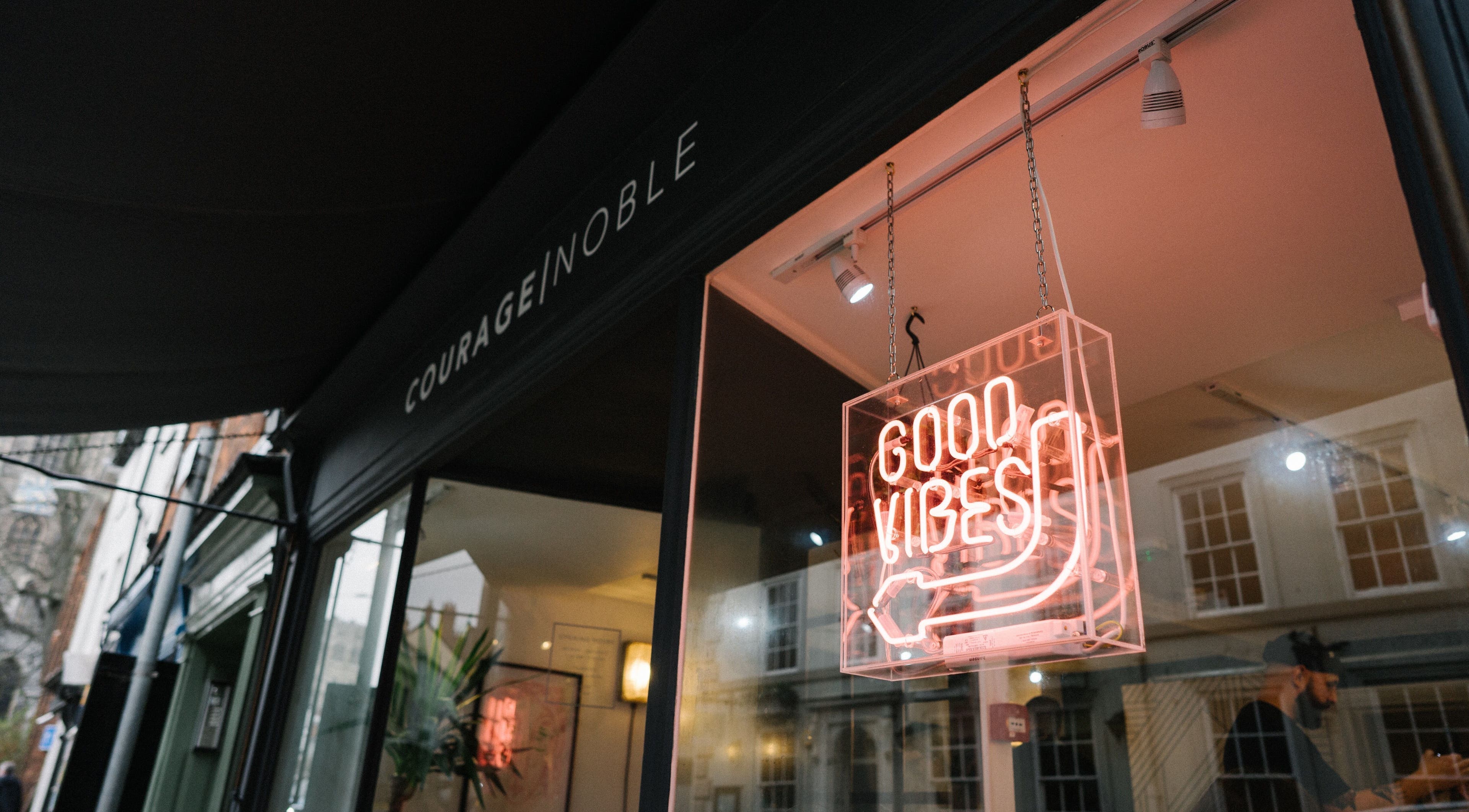 Entrance of Courage Noble | King Street, Norwich, England, GB with neon 'Good Vibes' sign.