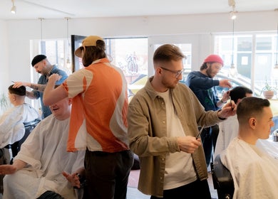Stylists at Courage Noble | King Street in Norwich, England, GB shaping modern haircuts for men in a bright salon.