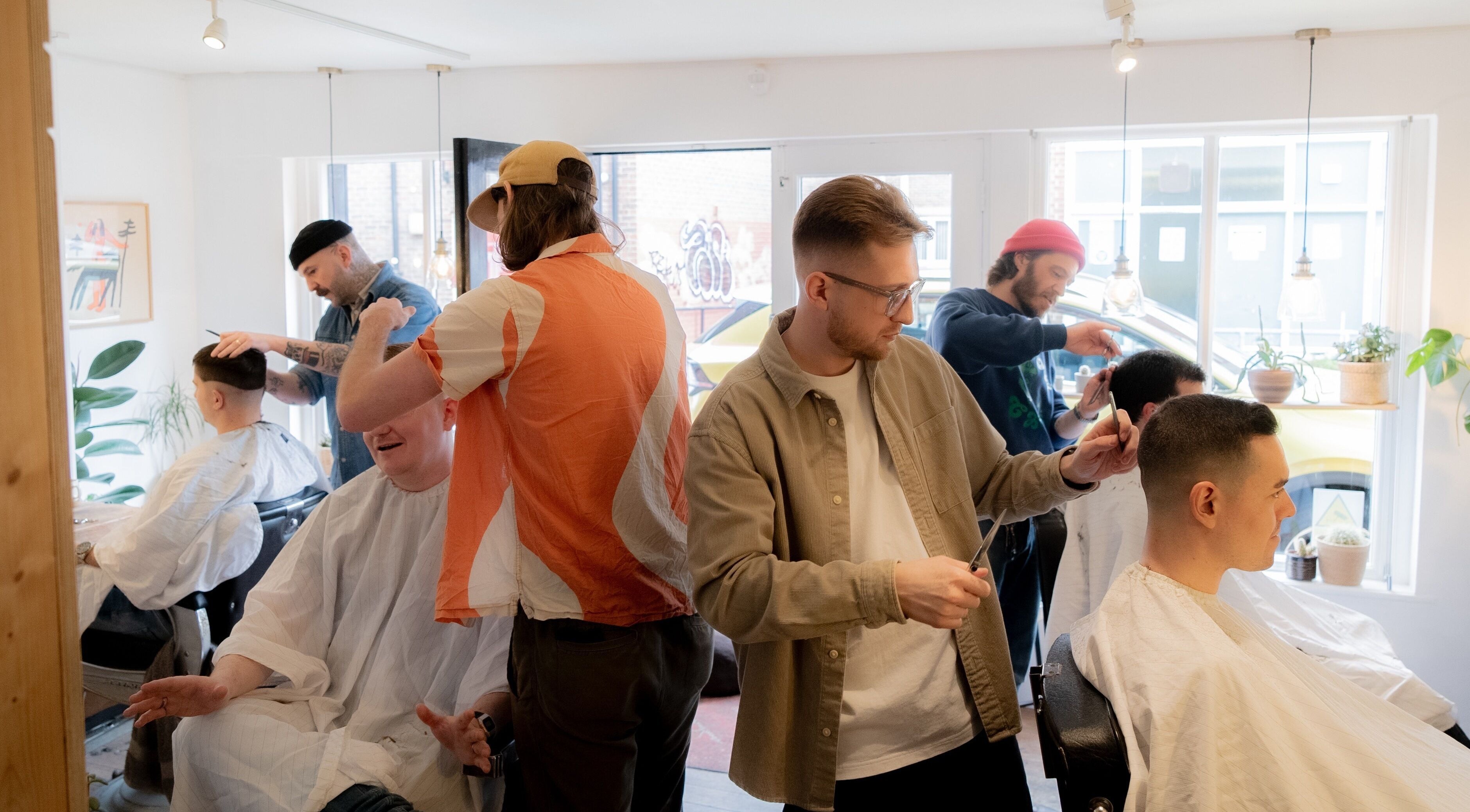 Stylists at Courage Noble | King Street in Norwich, England, GB shaping modern haircuts for men in a bright salon.