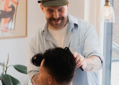 Barber styling hair at Courage Noble | King Street, Norwich, England, GB in a bright, modern salon.