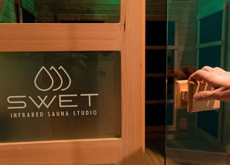 Hand opens sauna door at SWET Infrared Sauna Studio - Forest Hills, Grand Rapids, Michigan, US.