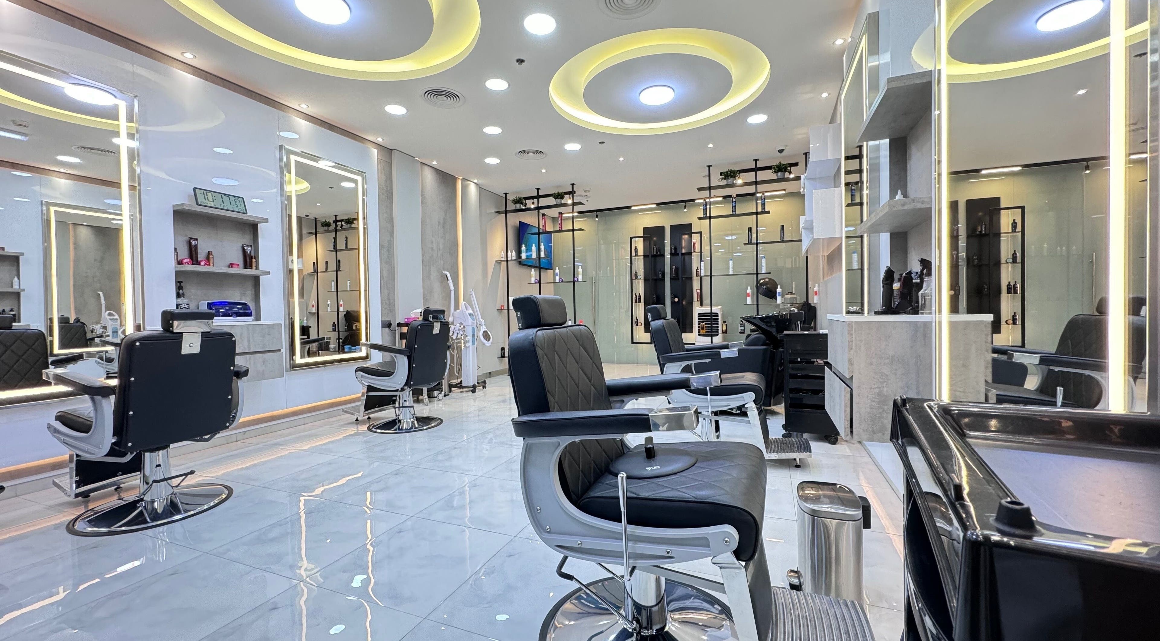 Bright, modern interior of Aleph Gents Salon DMCC in Dubai, AE with sleek black chairs and illuminated mirrors.