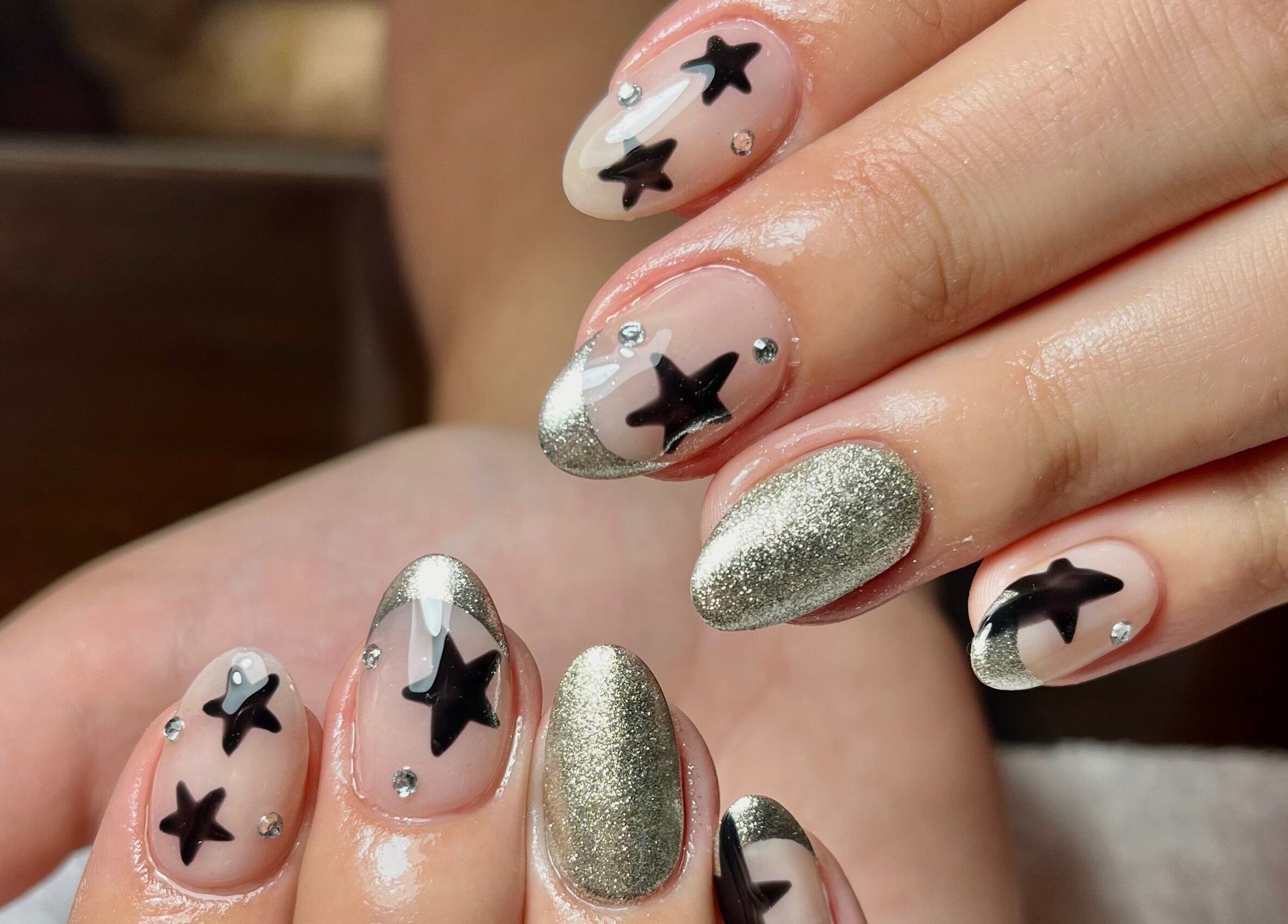 Diseño de uñas con estrellas negras y purpurina en Whale Nails, Ituzaingó, Provincia de Buenos Aires, AR.