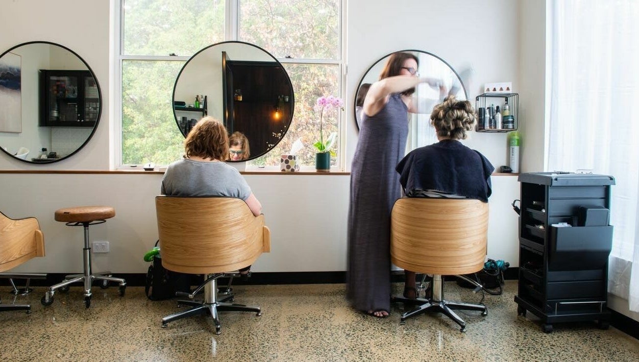 Stylish interior of RC Designs hair salon in Paddington, Queensland, AU with clients and stylist in action.