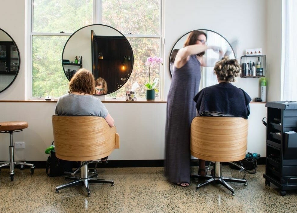 Stylish interior of RC Designs hair salon in Paddington, Queensland, AU with clients and stylist in action.