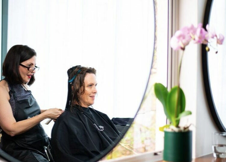 Hairdresser styling at RC Designs in Paddington, Queensland, AU near a window with a potted plant.