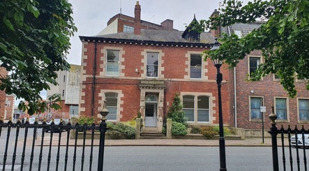 Charming red-brick building housing CL Body Therapy in Carlisle, England, GB, surrounded by greenery.