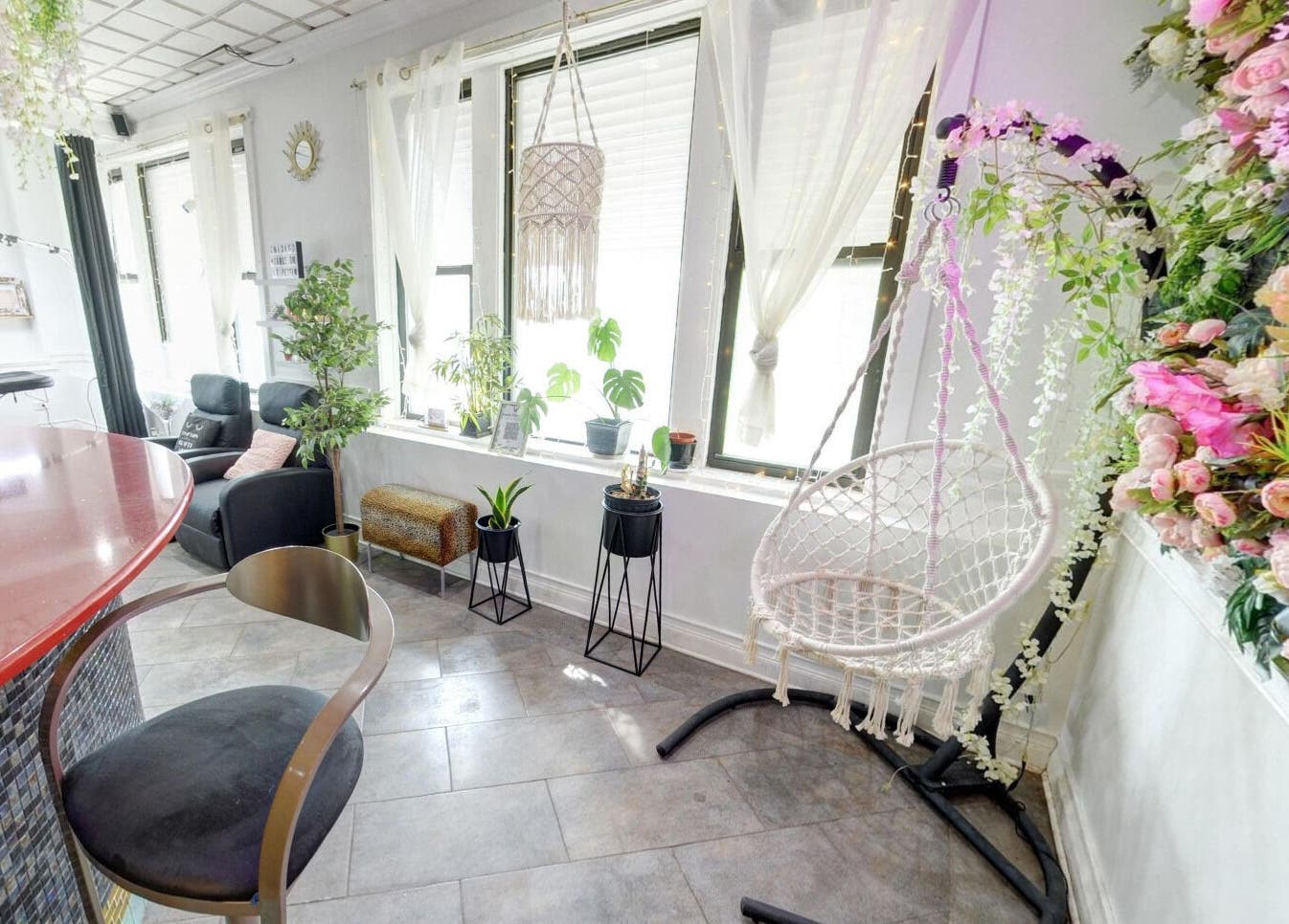 Relaxing corner at Beauty Vibez Studio in Chicago, Illinois, US with hanging chair and floral decor.