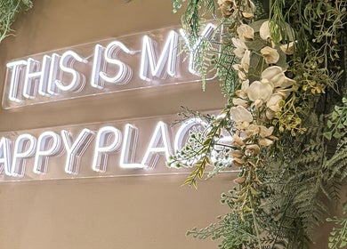 Neon sign 'This is my happy place' surrounded by greenery at Mirrored by Melissa | Root Rituals, Webster, New York, US.