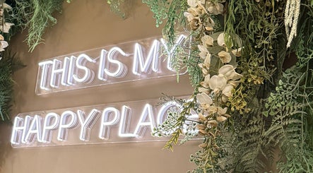 Neon sign 'This is my happy place' at Mirrored by Melissa | Root Rituals, Webster, New York, US amidst greenery.