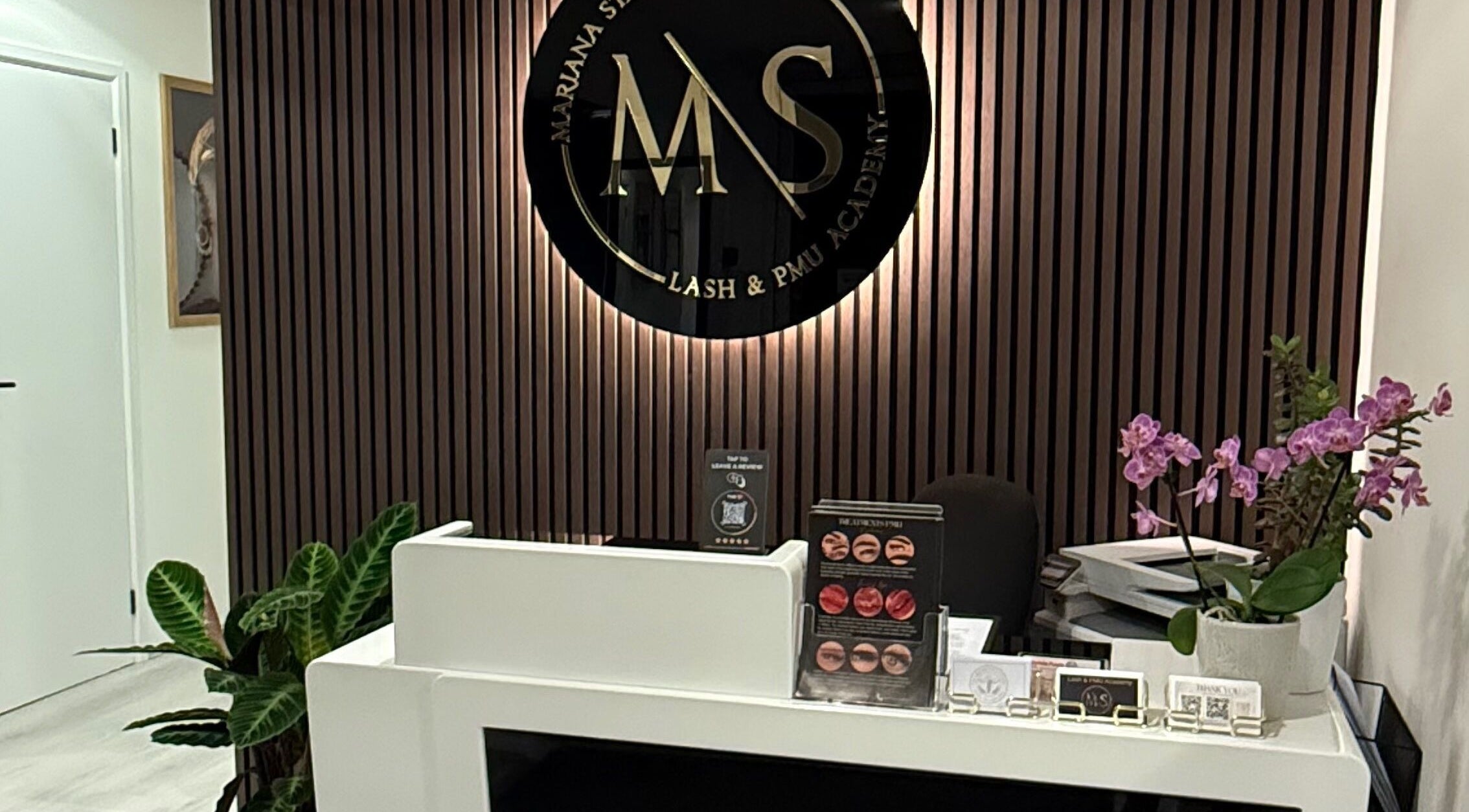 Reception desk at Lash and PMU Academy in Reading, England, GB with elegant decor and signage.