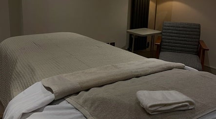 Calm treatment room at Charlie Perry Skin, London, England, GB, featuring a massage table and cozy chair.