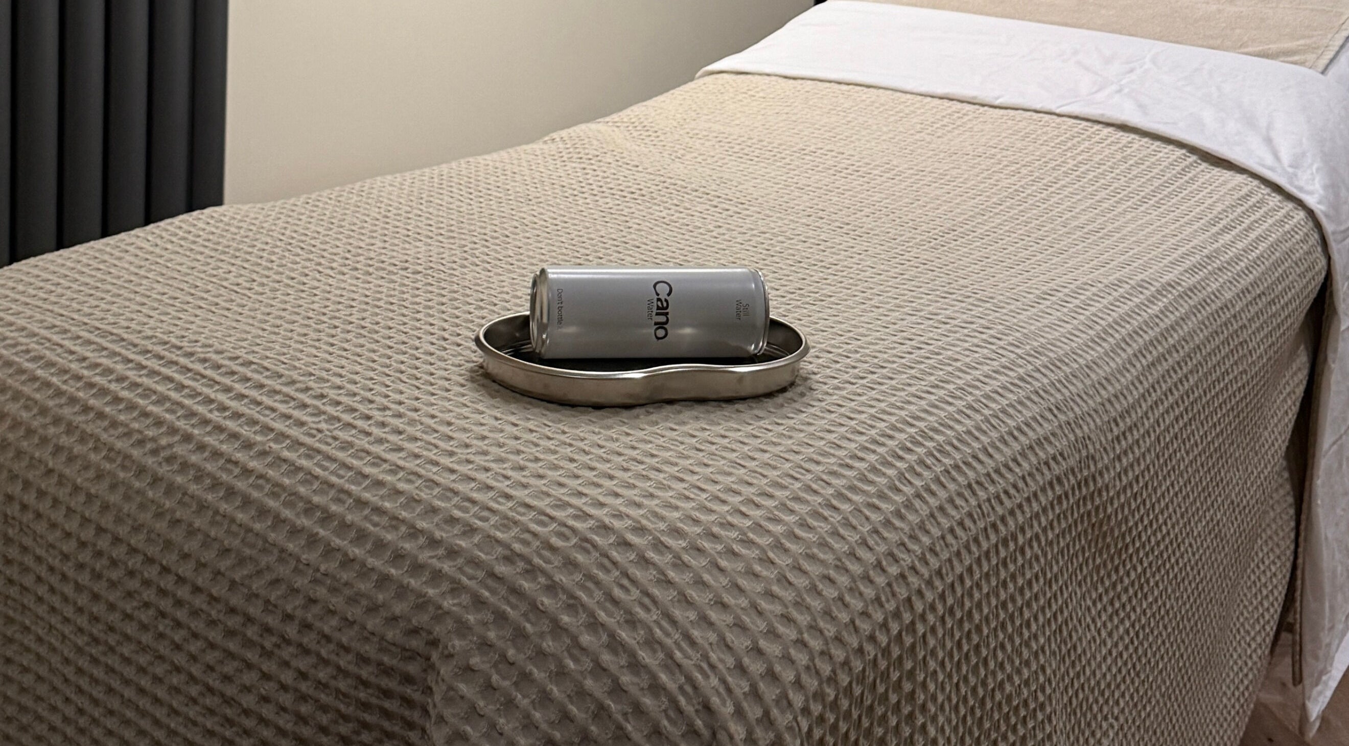 Comfortable treatment bed at Charlie Perry Skin, London, England, GB, with a can resting on a tray.