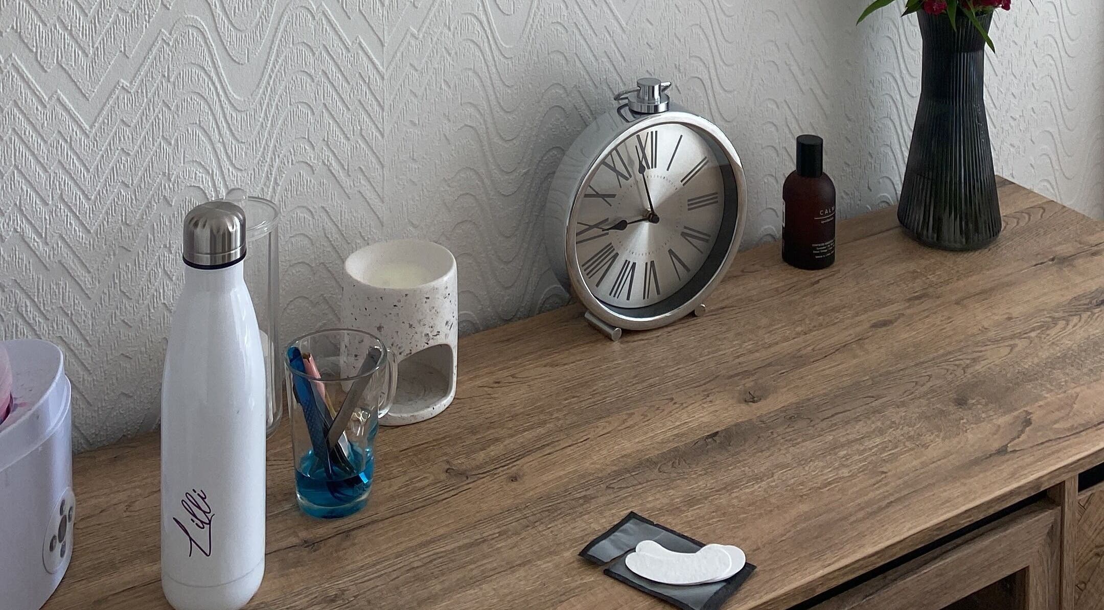 Stylish desk at Lashes & Brows By Lil, Hoddesdon, England, GB featuring clock and beauty tools.