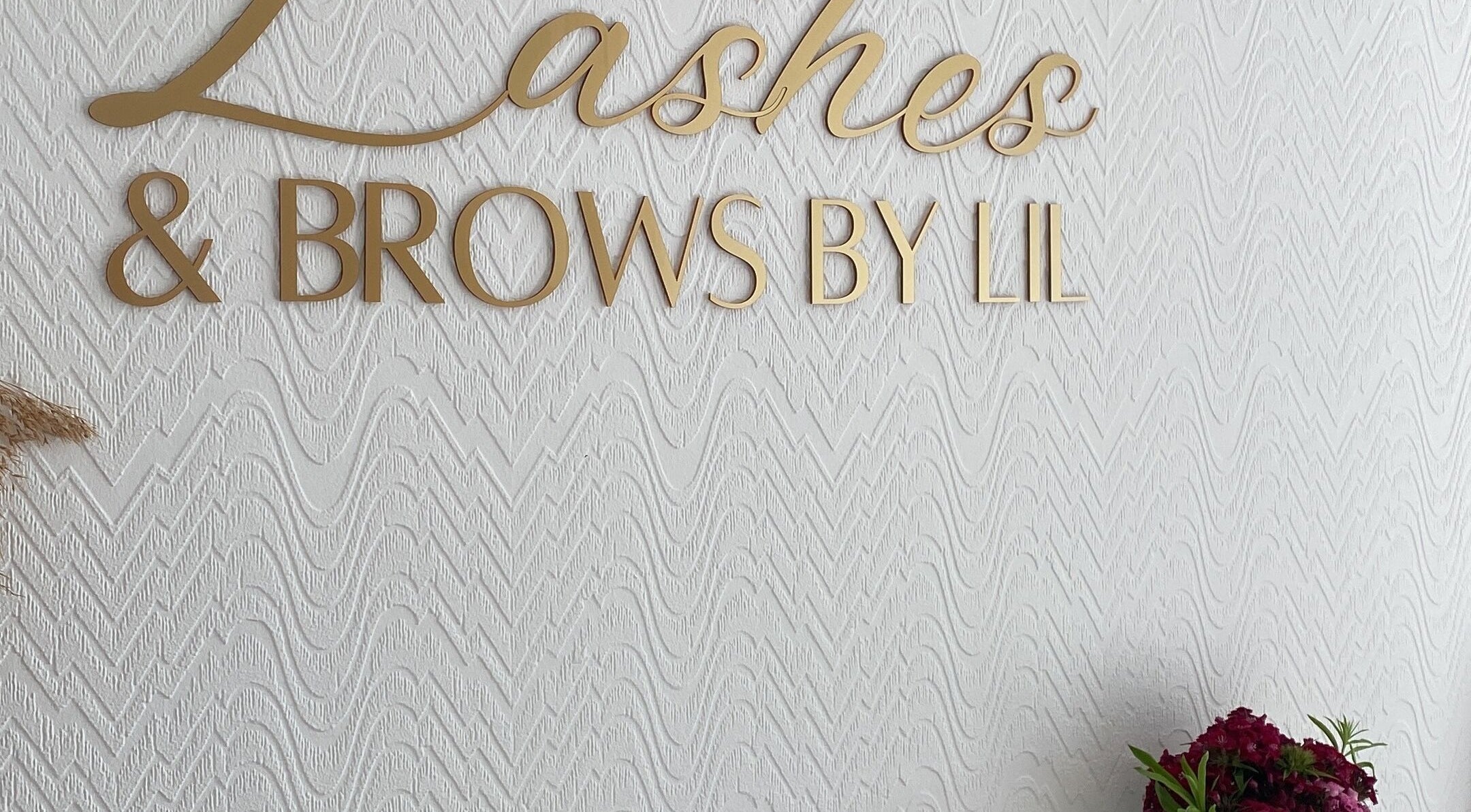 Gold sign of Lashes & Brows By Lil on a textured wall in Hoddesdon, England, GB.