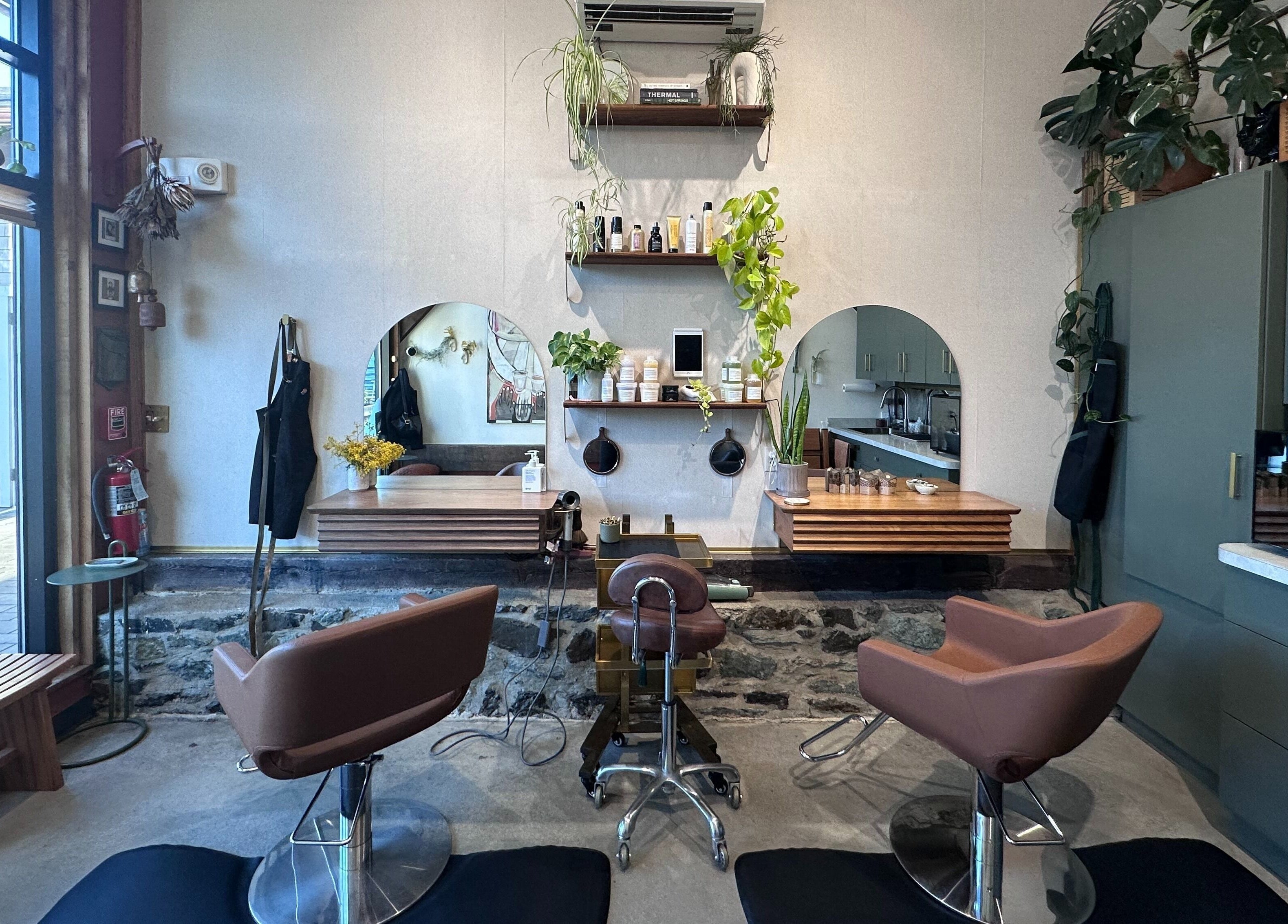 Modern interior of Bellwether Salon in Boston, Massachusetts, US with stylish chairs and lush greenery.