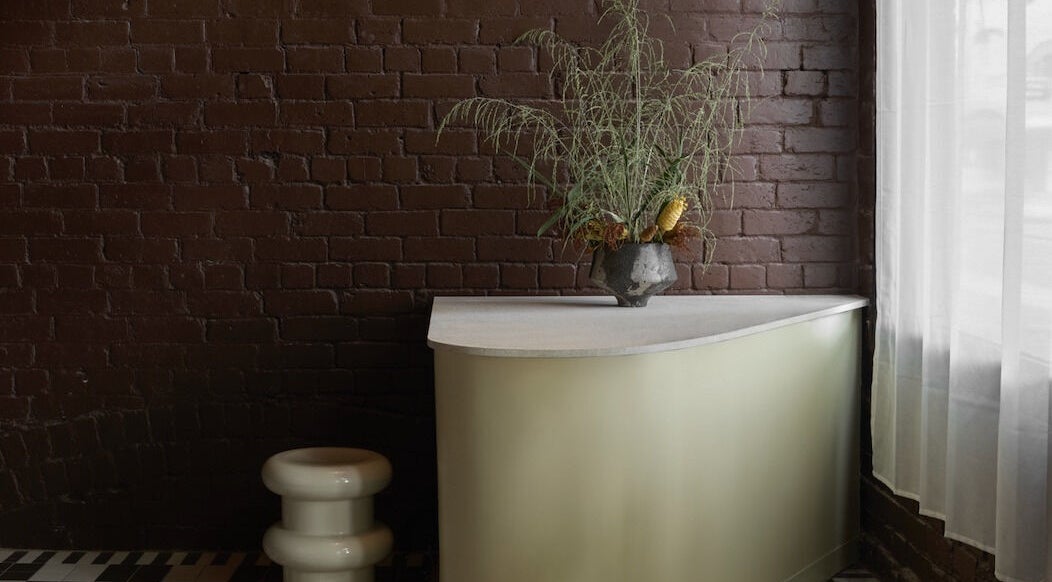 Stylish reception area at Nimbus Co Fitzroy, Melbourne, Victoria, AU with a modern desk and greenery.